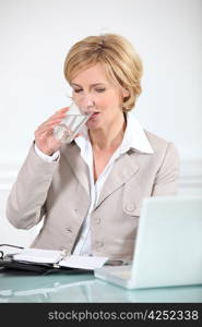 Businesswoman drinking a glass of water at her desk