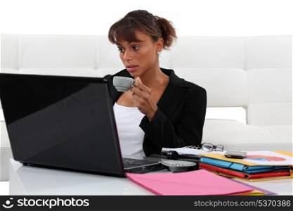 Businesswoman drinking coffee whilst working