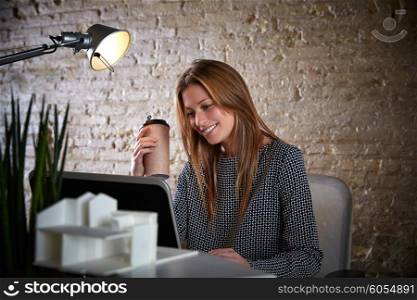 Businesswoman drinking coffee with laptop computer at office