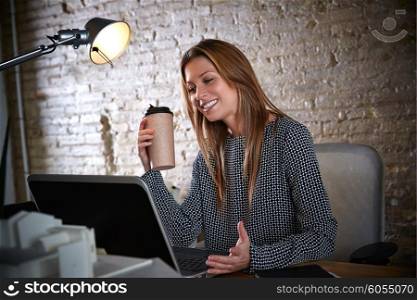 Businesswoman drinking coffee with laptop computer at office