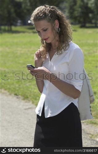 Businesswoman enjoying her lunch break in the park and sending a text message on her mobile phone