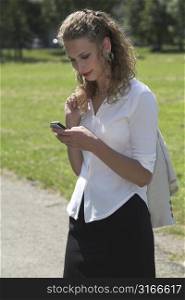 Businesswoman enjoying her lunch break in the park and sending a text message on her mobile phone