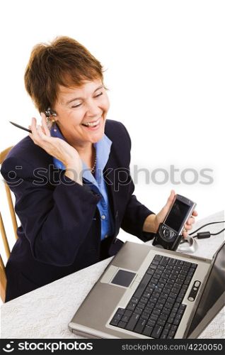 Businesswoman enjoying talking on her hands free set while transferring data from her PDA to her laptop computer.