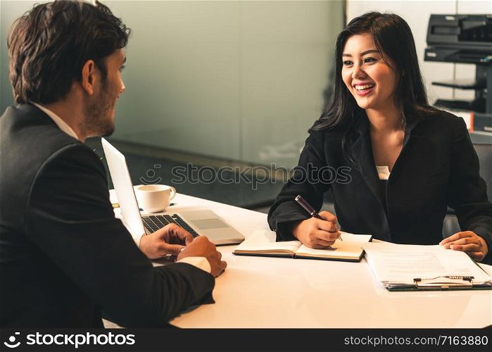 Businesswoman from human resources department is interviewing businessman candidate for job application in the meeting room while considering his CV resume document. Employee hiring business concept.