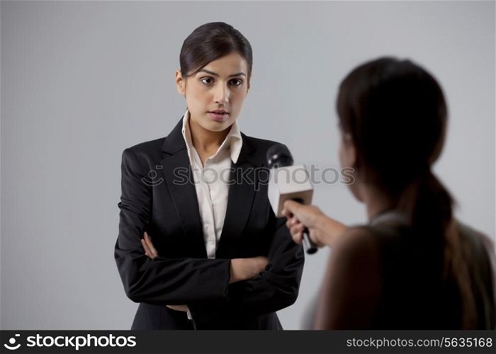 Businesswoman giving an interview to a reporter against colored background