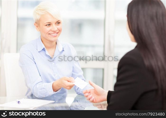 Businesswoman giving her business card to another businesswoman in office