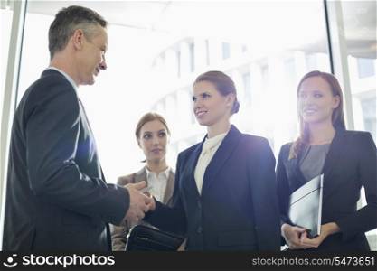 Businesswoman giving her card to businessman in office
