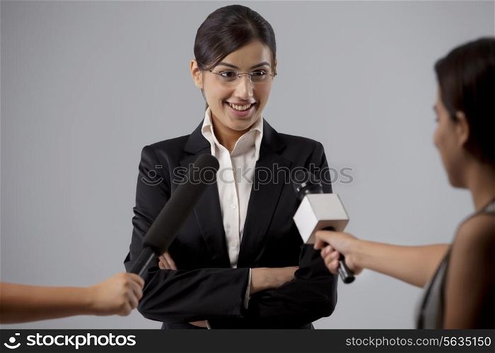 Businesswoman giving interview against colored background