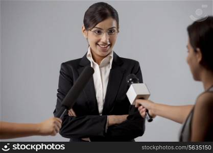 Businesswoman giving interview against colored background