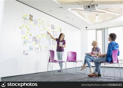 Businesswoman giving presentation to colleagues in creative office space
