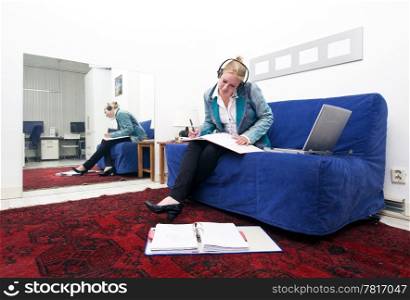Businesswoman going over thick dossiers on a couch in a homely office environment