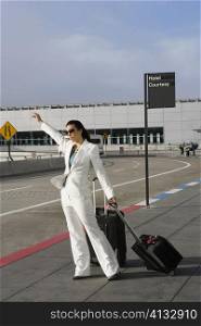 Businesswoman hailing a taxi outside an airport