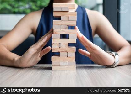 Businesswoman hand cover wooden block on the tower. Business planning, Risk Management, Solution and strategy Concepts