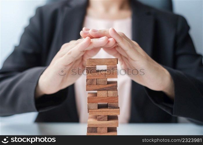 Businesswoman hand cover wooden block on the tower. Business planning, Risk Management, Solution, insurance and strategy Concepts