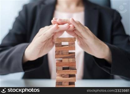 Businesswoman hand cover wooden block on the tower. Business planning, Risk Management, Solution, insurance and strategy Concepts