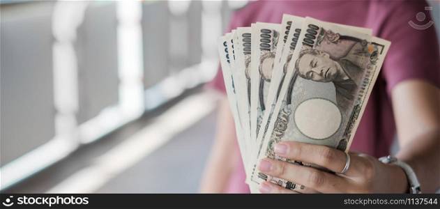 Businesswoman hand holding Japanese Yen banknote stack. business, money, investment , finance and payment concepts