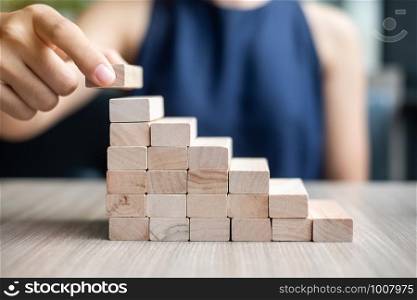 Businesswoman hand placing or pulling wooden block on the building. Business planning, Risk Management, Solution and strategy Concepts