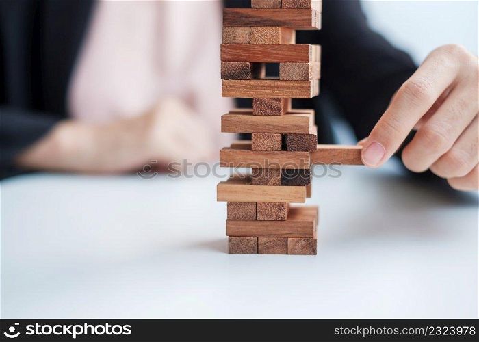 Businesswoman hand placing or pulling wooden block on the tower. Business planning, Risk Management, Solution and strategy Concepts