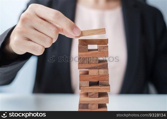 Businesswoman hand placing or pulling wooden block on the tower. Business planning, Risk Management, Solution and strategy Concepts