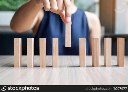 Businesswoman hand placing or pulling wooden Dominoes. Business, Risk Management, Solution and strategy Concepts
