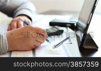 Businesswoman hands working with charts on tablet computer at her desk