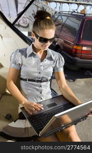 businesswoman has a fan with laptop in black car