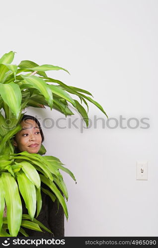 Businesswoman hiding behind office plant