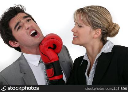 businesswoman hitting a man with a boxing glove