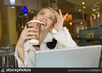 Businesswoman holding a disposable cup and smiling in a restaurant