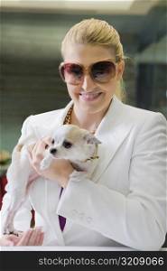 Businesswoman holding a puppy and smiling