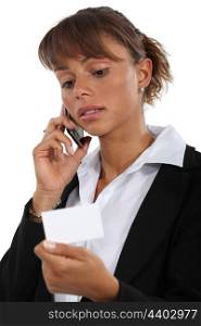 businesswoman holding a visit card and talking on her cell