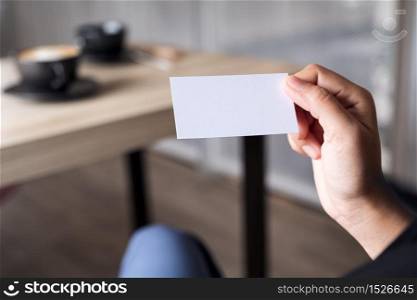 Businesswoman holding an empty business card while sitting in office