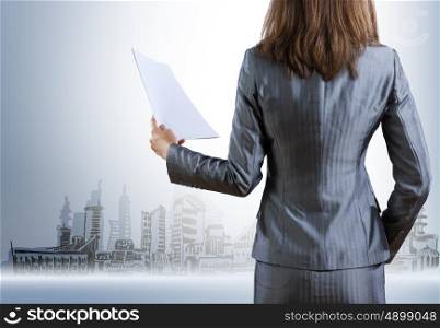 Businesswoman holding documents. Rear view of businesswoman with papers in hand