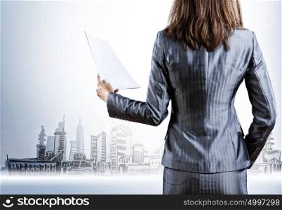 Businesswoman holding documents. Rear view of businesswoman with papers in hand
