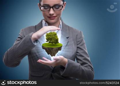 Businesswoman holding floating island with tree