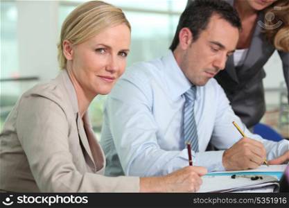 Businesswoman holding pen sat next to colleague