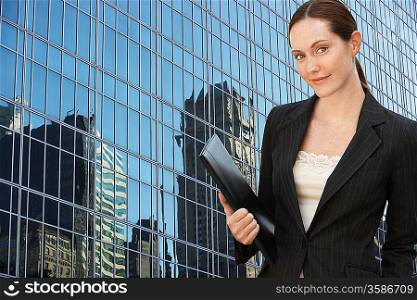 Businesswoman holding portfolio outside office building portrait