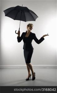 Businesswoman holding umbrella and gesturing.