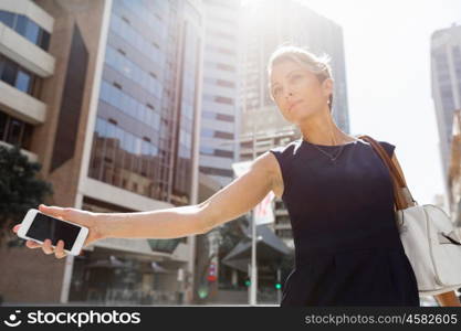 Businesswoman in a city street waving for taxi. I will be there in time for my meeting