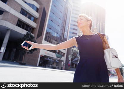 Businesswoman in a city street waving for taxi. I will be there in time for my meeting