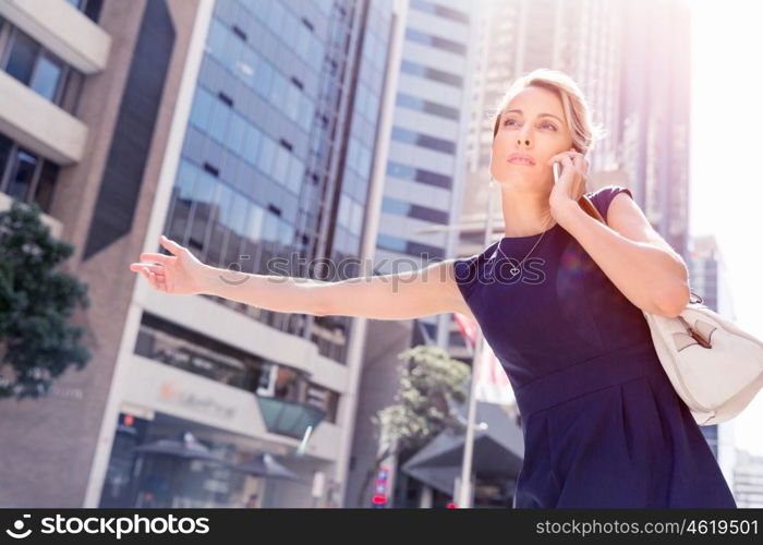 Businesswoman in a city street waving for taxi. I will be there in time for my meeting