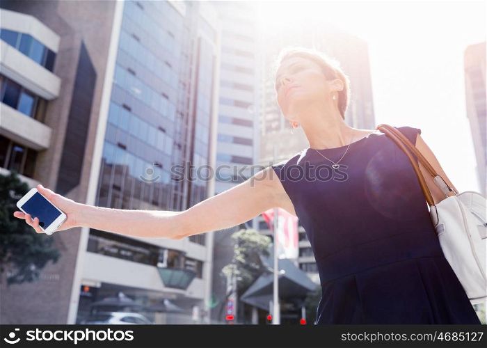 Businesswoman in a city street waving for taxi. I will be there in time for my meeting