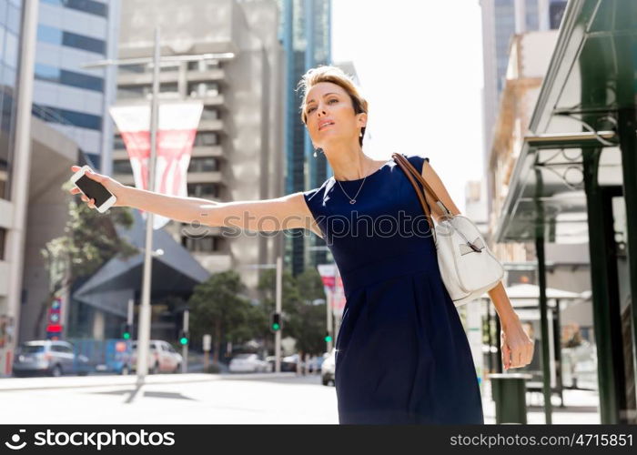 Businesswoman in a city street waving for taxi. I will be there in time for my meeting