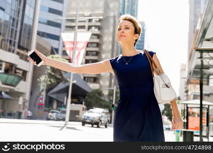 Businesswoman in a city street waving for taxi. I will be there in time for my meeting