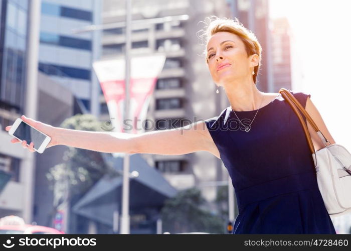 Businesswoman in a city street waving for taxi. I will be there in time for my meeting