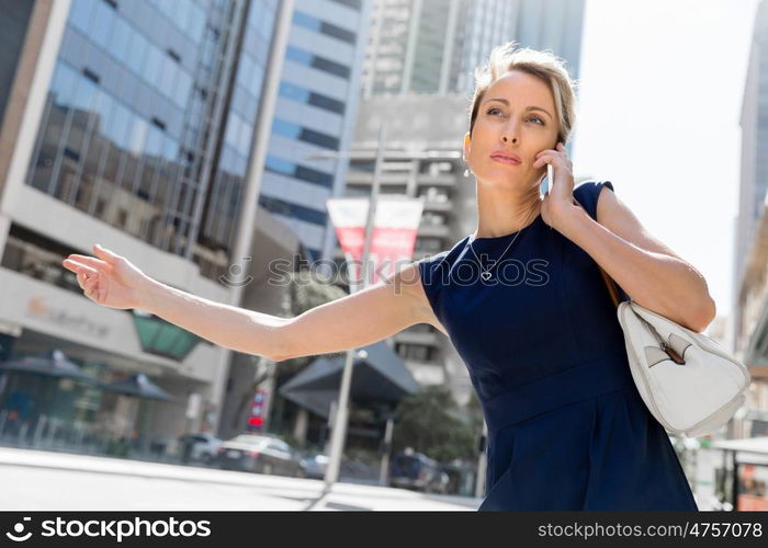 Businesswoman in a city street waving for taxi. I will be there in time for my meeting