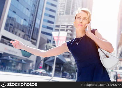 Businesswoman in a city street waving for taxi. I will be there in time for my meeting