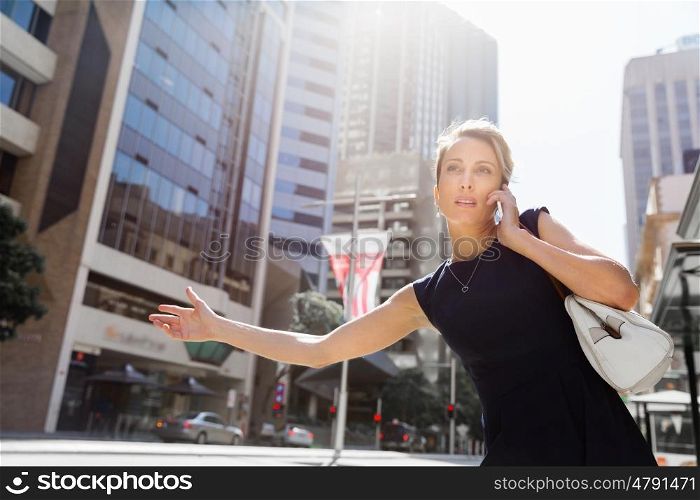 Businesswoman in a city street waving for taxi. I will be there in time for my meeting