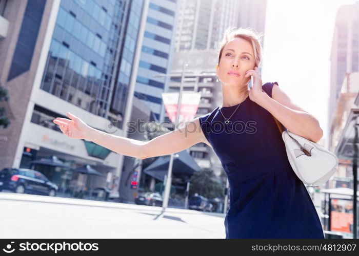 Businesswoman in a city street waving for taxi. I will be there in time for my meeting