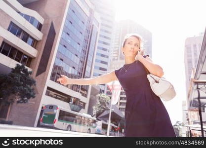 Businesswoman in a city street waving for taxi. I will be there in time for my meeting